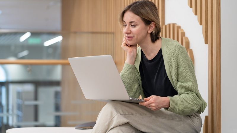 Pensive thoughtful middle-aged woman looking at laptop screen reading document while working in coworking space, female freelance writer using computer writing online content. Mature freelance worker