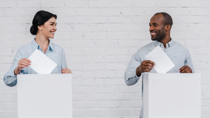 happy woman and african american man voting near brick wall